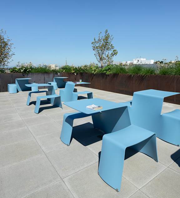 an outdoor seating area with blue tables and chairs on a roof at Cedar Crossing, Seattle, WA, 98115