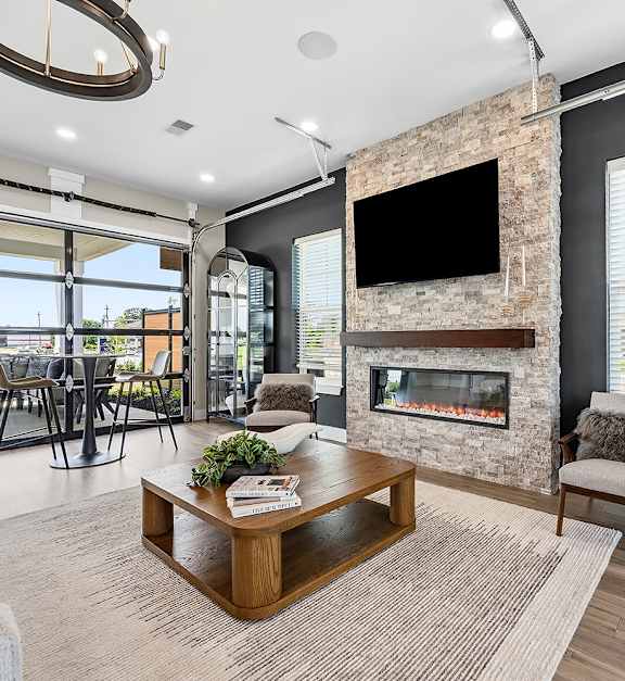 A modern living room with a stone fireplace and a flat screen TV mounted above it.