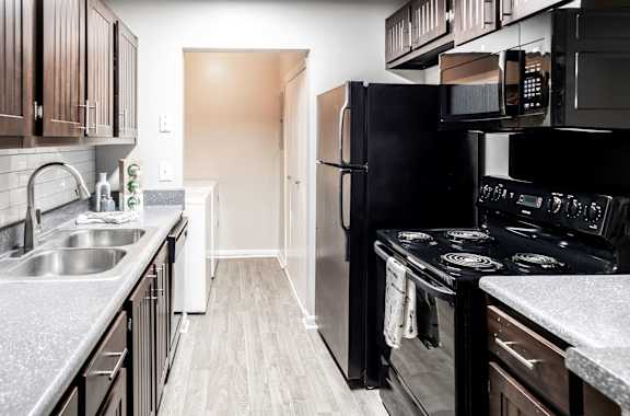 Galley kitchen with black appliances located at Addison on Cobblestone located in Fayetteville, GA 30215