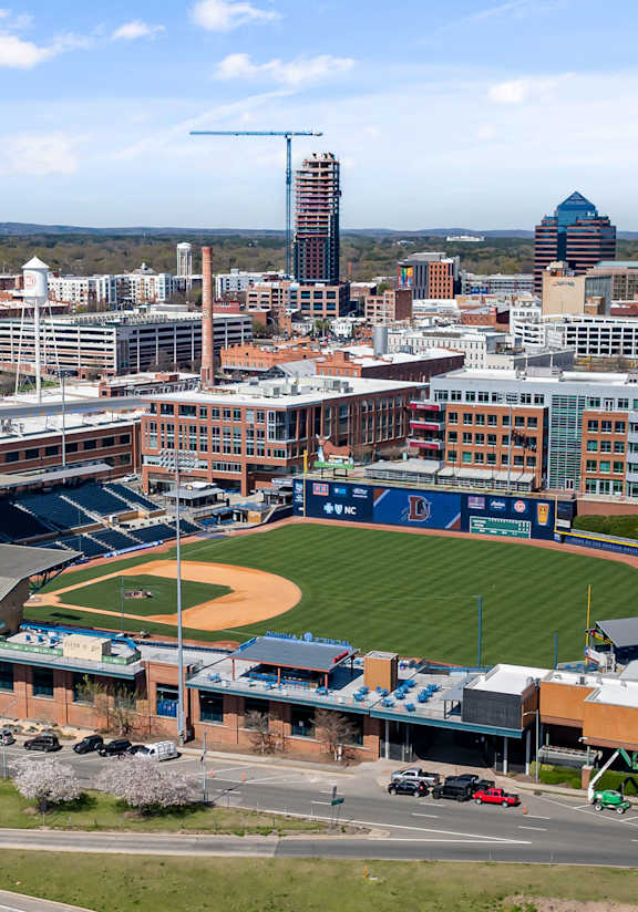 A baseball stadium is surrounded by buildings and roads.