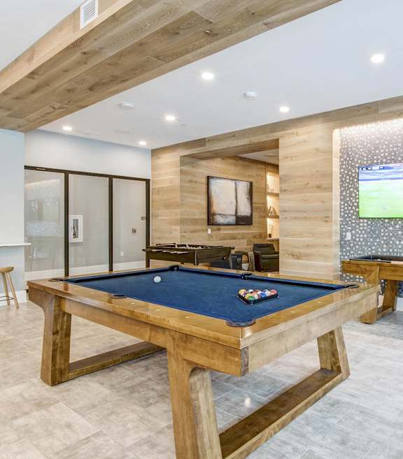 A pool table in a room with a TV and a bench.