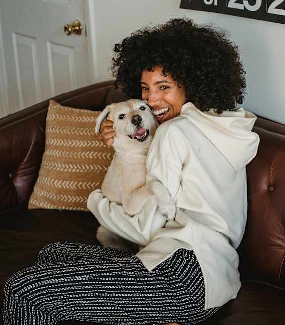 A person is sitting on the grass with a happy dog.