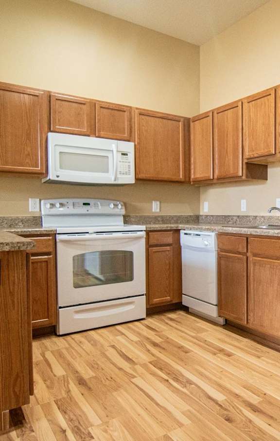 A kitchen with wooden cabinets and a white refrigerator.at Cottages at Johnston Commons, Johnston, 50131