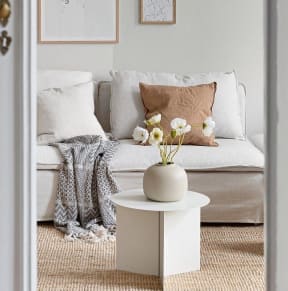 A white door opens to a living room with a couch and a coffee table.
