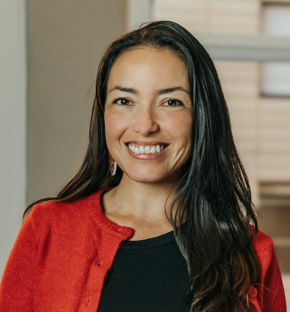 a woman in a red jacket and black shirt is smiling at the camera