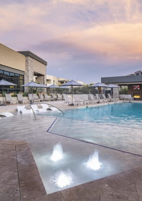 a swimming pool with chaise lounge chairs and umbrellas in front of a hotel