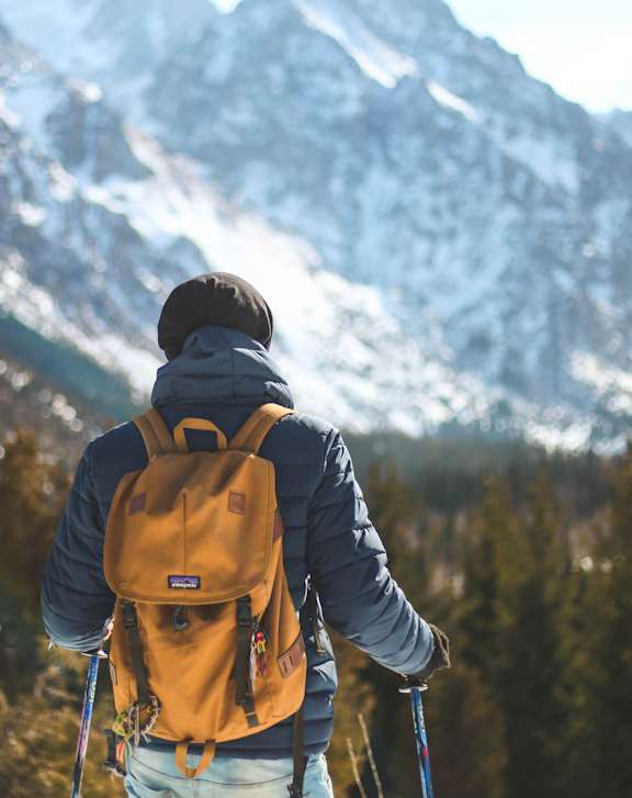 A man with a backpack is hiking in a snowy mountainous area.