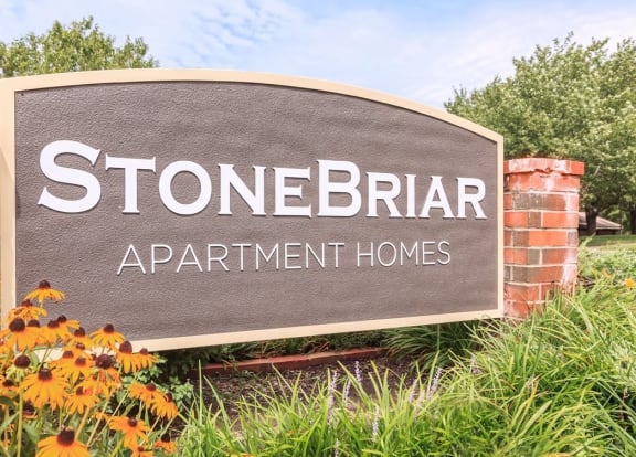 a sign for stonebrae apartment homes in front of flowers