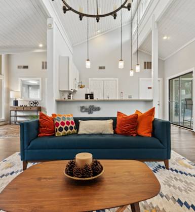 A blue couch with a bowl of fruit on it sits in a living room.