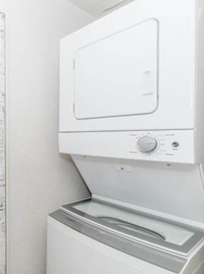 A white dryer is next to a white wall with a list of items on it.