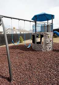 A playground with a blue slide and a grey structure.
