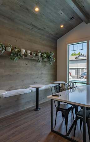 A lounge with tables and chairs and a large window overlooking a pool at Sandyplace Apartment Homes, Sandy