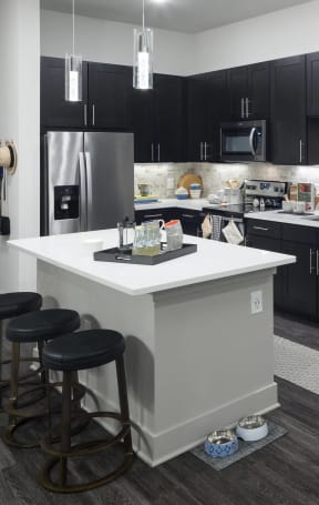 a kitchen with black cabinets and a white island with stools