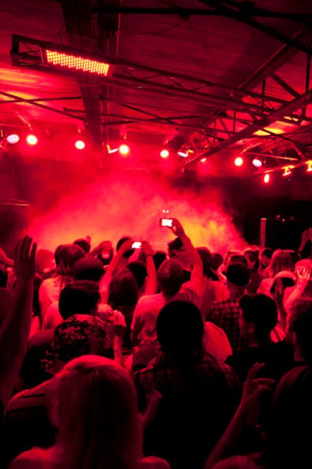 A crowd of people at a concert with red lighting.