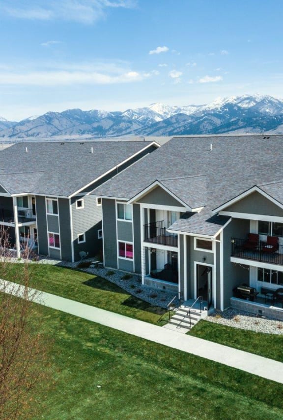 an aerial view of three apartment buildings with mountains in the background at Madison Park, Bozeman