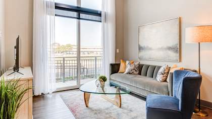 A living room with a blue chair and a glass table.