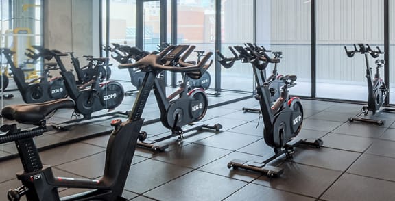 a man and a woman riding exercise bikes in a gym