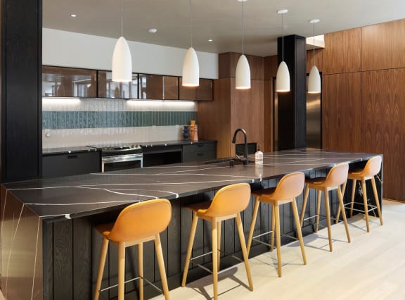 a kitchen with a long black countertop and yellow bar stools