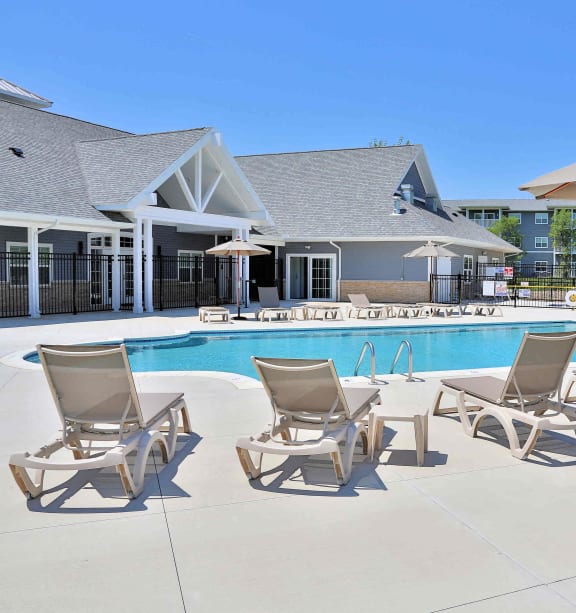 a pool with chairs and umbrellas next to a house