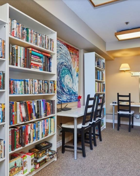 a library with bookshelves and a dining room with a table and chairs at Huntington Terrace North Senior, California, 92648