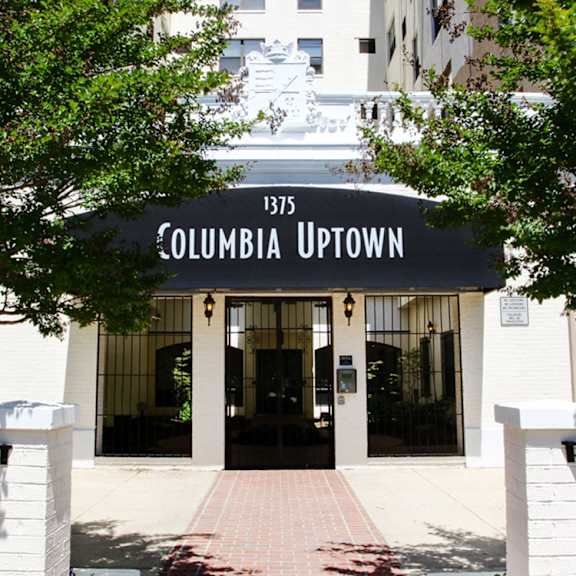 A foosball table is in the middle of a room with a brick fireplace and a chandelier. at Columbia Uptown Apartments, Washington, Washington DC