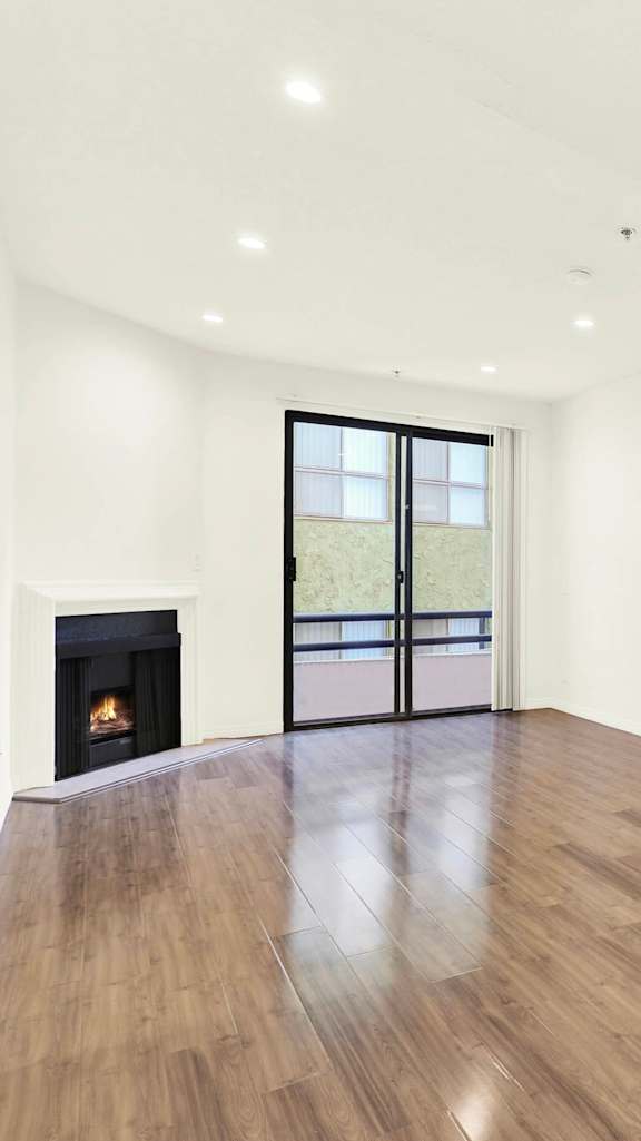 A bedroom with a large bed, a dresser, and a mirror at Park Rochester Apartments Westwood, Los Angeles, CA