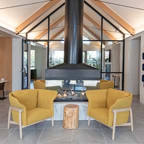 A modern living room with a yellow chair and a fireplace.