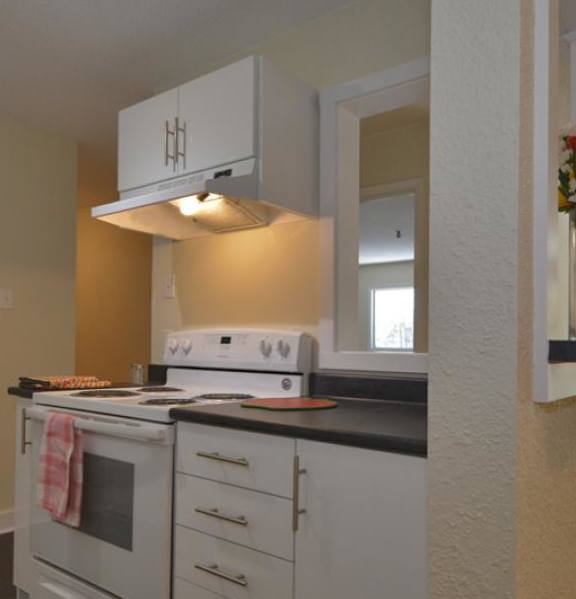 A modern kitchen with a stainless steel refrigerator and wooden flooring.