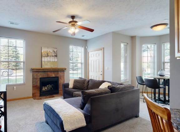 a living room with a couch and a fireplace and a ceiling fan