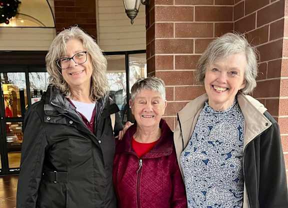 Three women standing in front of a building entrance at River Commons Senior Living, Redding