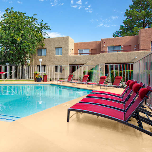A pool with red sunshades and red lounge chairs.