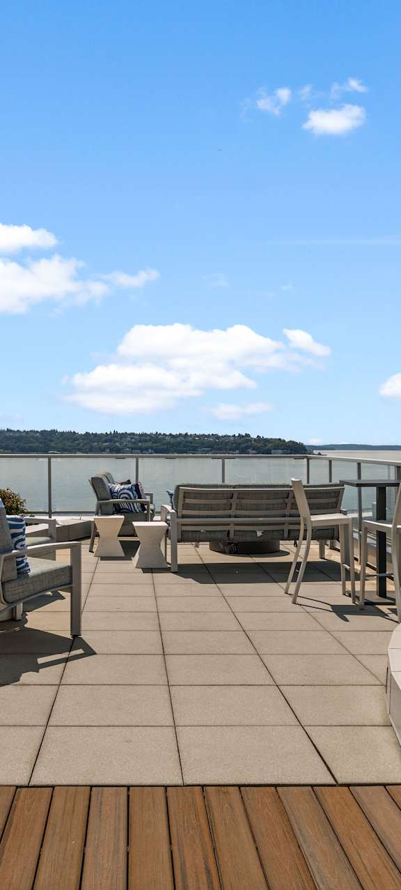 A patio with a table and chairs overlooking a body of water.