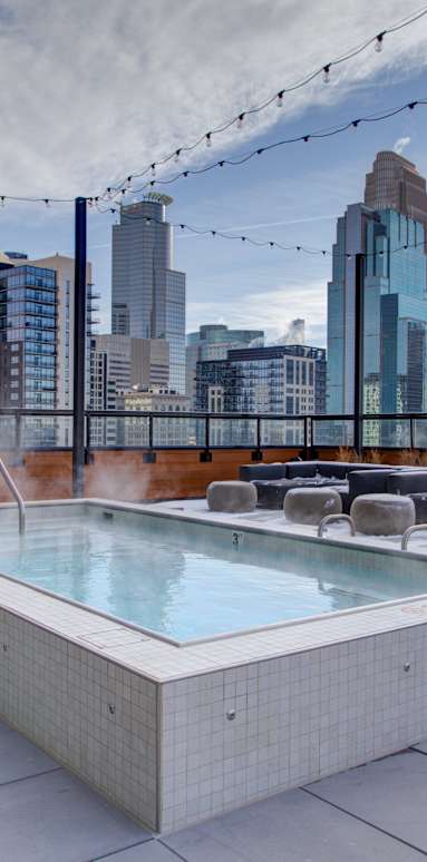 A hot tub on a rooftop with a city skyline in the background.