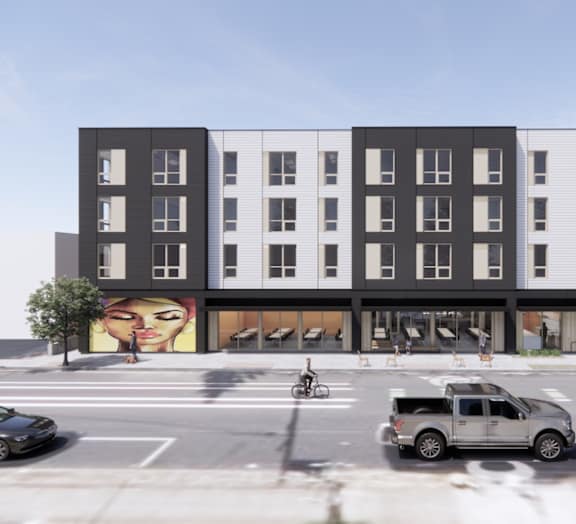 A street view of a building with cars and a mural on the side.
