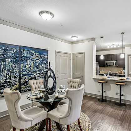 A dining room with a table set for two and a cityscape on the wall.