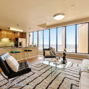 A modern living room with a black leather chair and a glass coffee table.