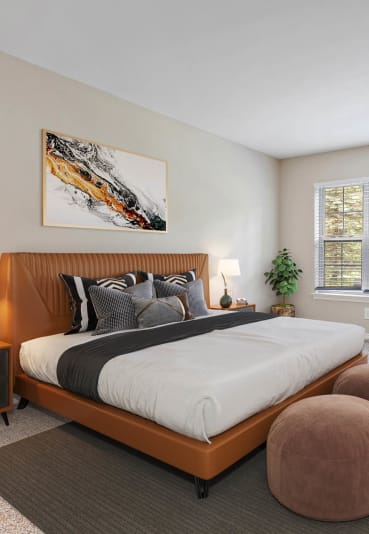 a bedroom with a bed and a chair in front of a window at Brandywine Apartments, West Bloomfield