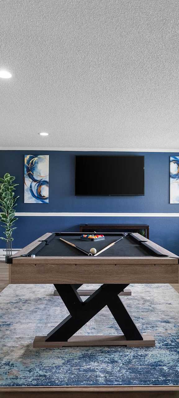 A room with a blue rug and a wooden table.