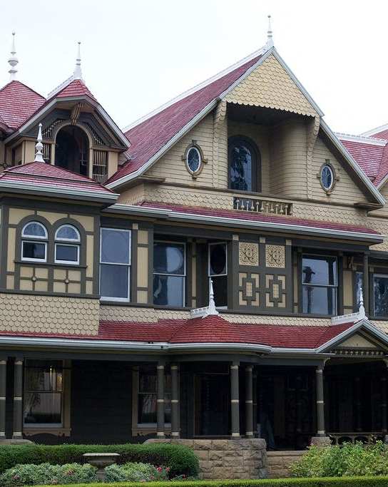 A Victorian style house with a red roof and a balcony.