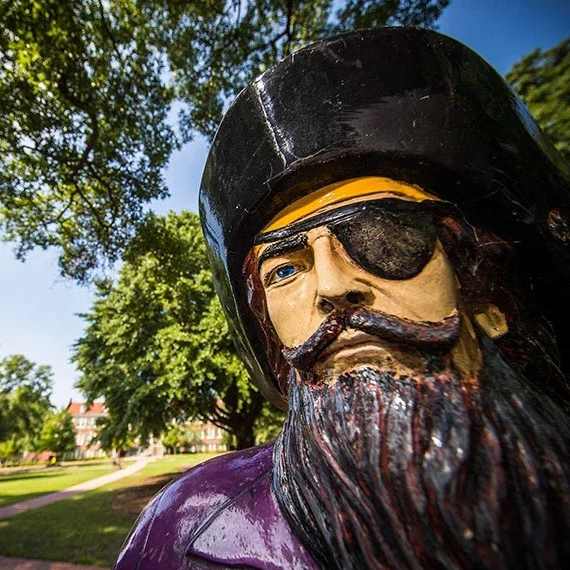 A statue of a man with a beard and sunglasses is in the foreground.