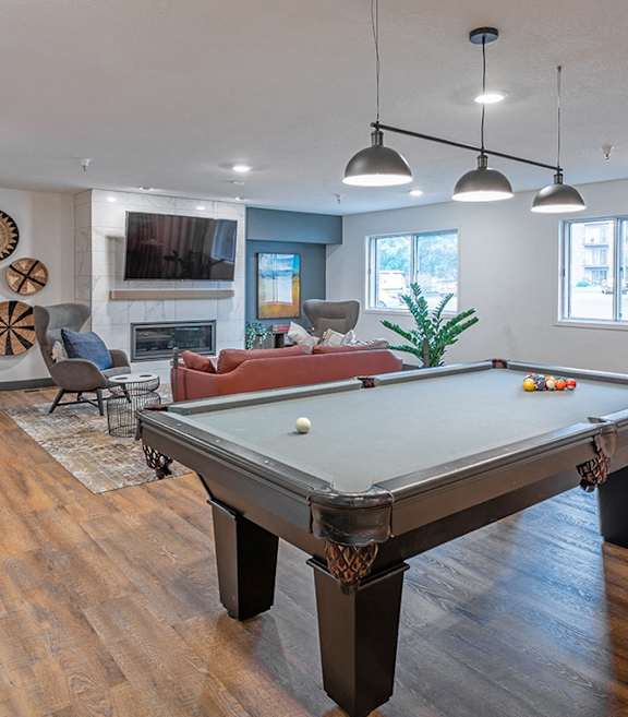 A pool table is in the middle of a room with wood flooring.