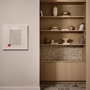 A room with a patterned carpet and a shelf with various items on it.