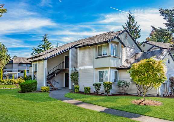 Exterior view of Sir Charles Court's apartment buildings, surrounded by green grass and trees in Beaverton, Oregon.