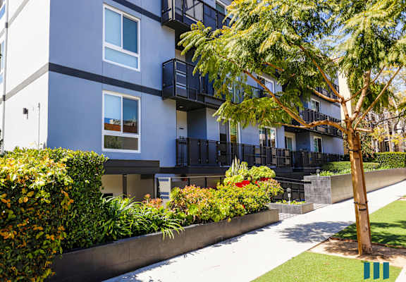 an exterior view of an apartment building with a sidewalk and landscaping