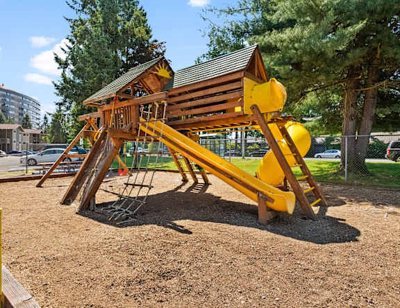 A playground with a wooden and yellow slide.