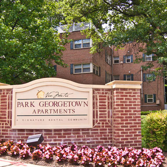 A brick building with a balcony and a tree in front. at Park Georgetown Apartments, Virginia