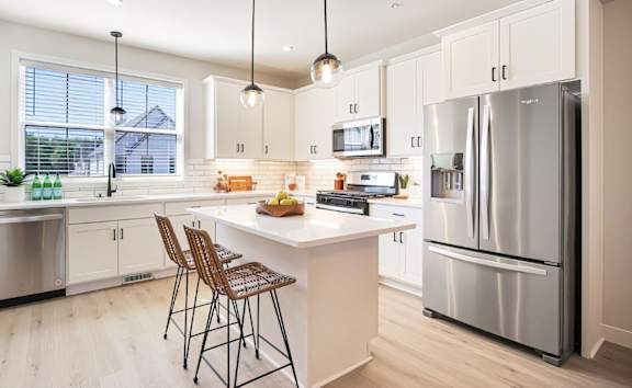 A modern kitchen with a white island and stainless steel appliances.