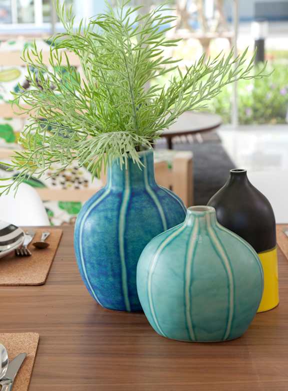 A dining table with blue bowls, plates and vases.