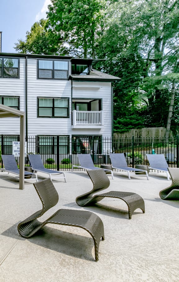 a patio with lounge chairs and tables in front of a building