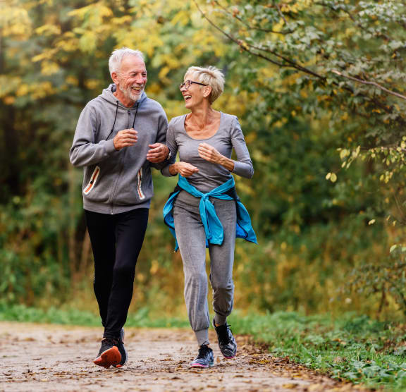 an older couple walking down a path in the woods